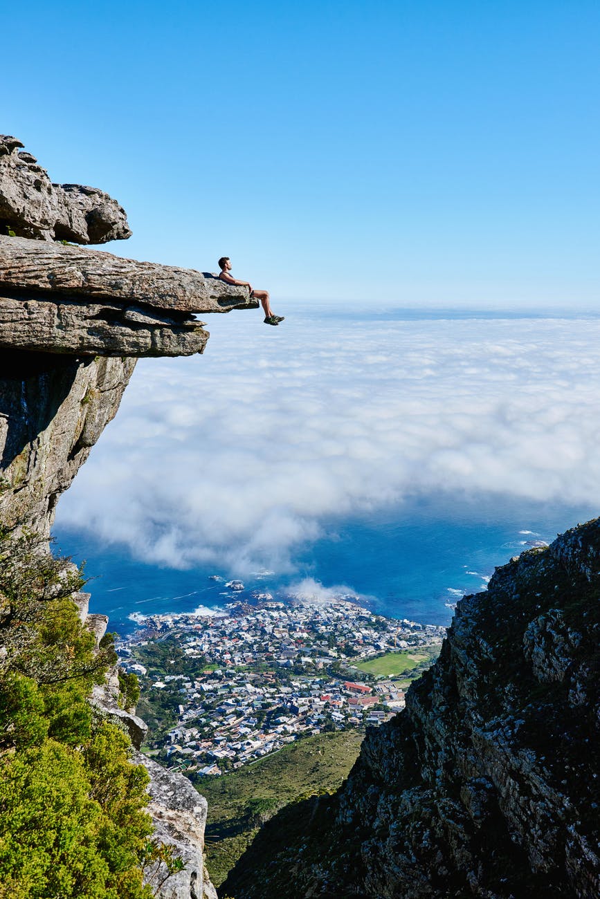 person sitting on mountain cliff