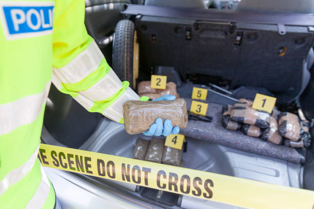 Police officer holding drug package discovered in the trunk of a car